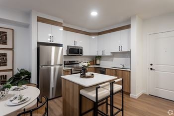 A modern kitchen with a stainless steel refrigerator, microwave, and white countertops.